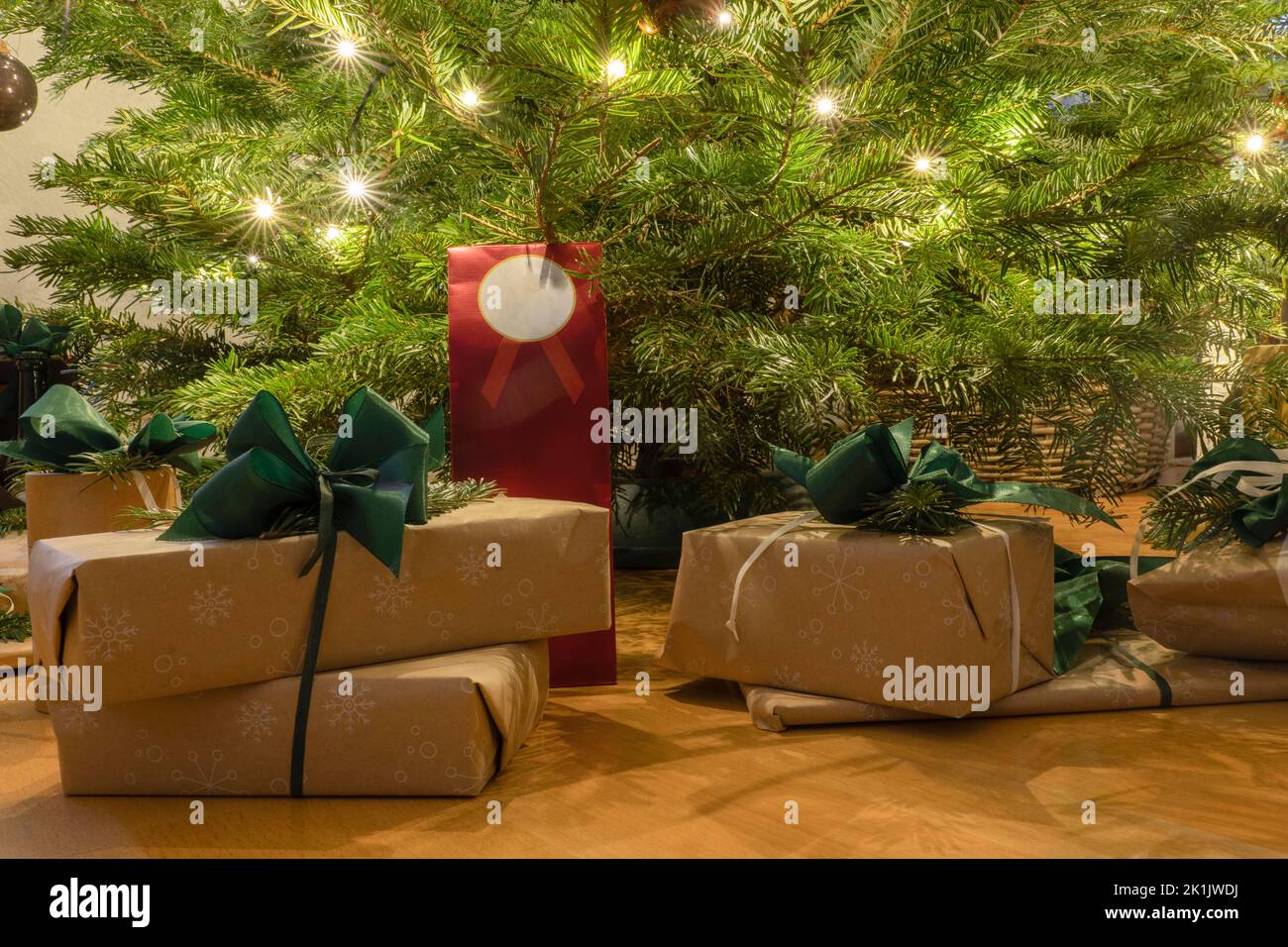 Regalos bellamente envueltos con arcos bajo el árbol de Navidad con estrellas de luz Foto de stock