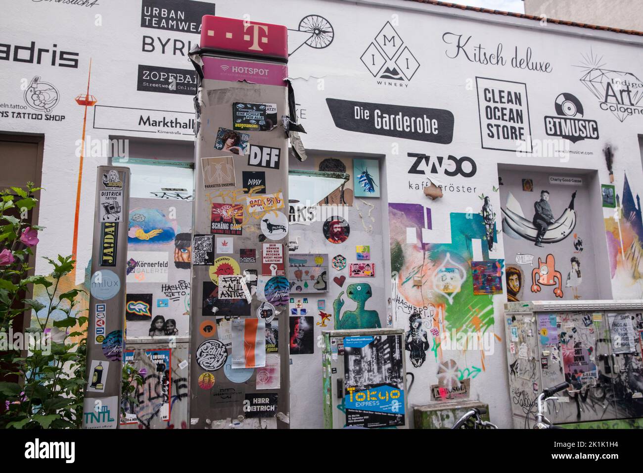 Pared de la casa y teléfono público con graffitis, pasta y logotipos de las tiendas situadas aquí, calle Koerner en el distrito de Ehrenfeld, Colonia, alemán Hausw Foto de stock