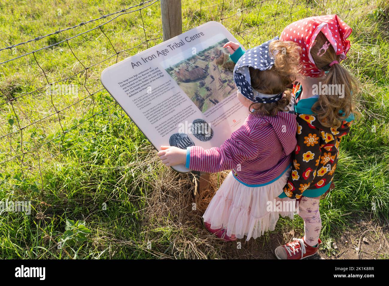 Dos pequeñas visitadoras de la ciudad romana de Silchester leyendo un panel de información sobre el antiguo centro tribal de la edad de hierro en el mismo sitio. REINO UNIDO Foto de stock