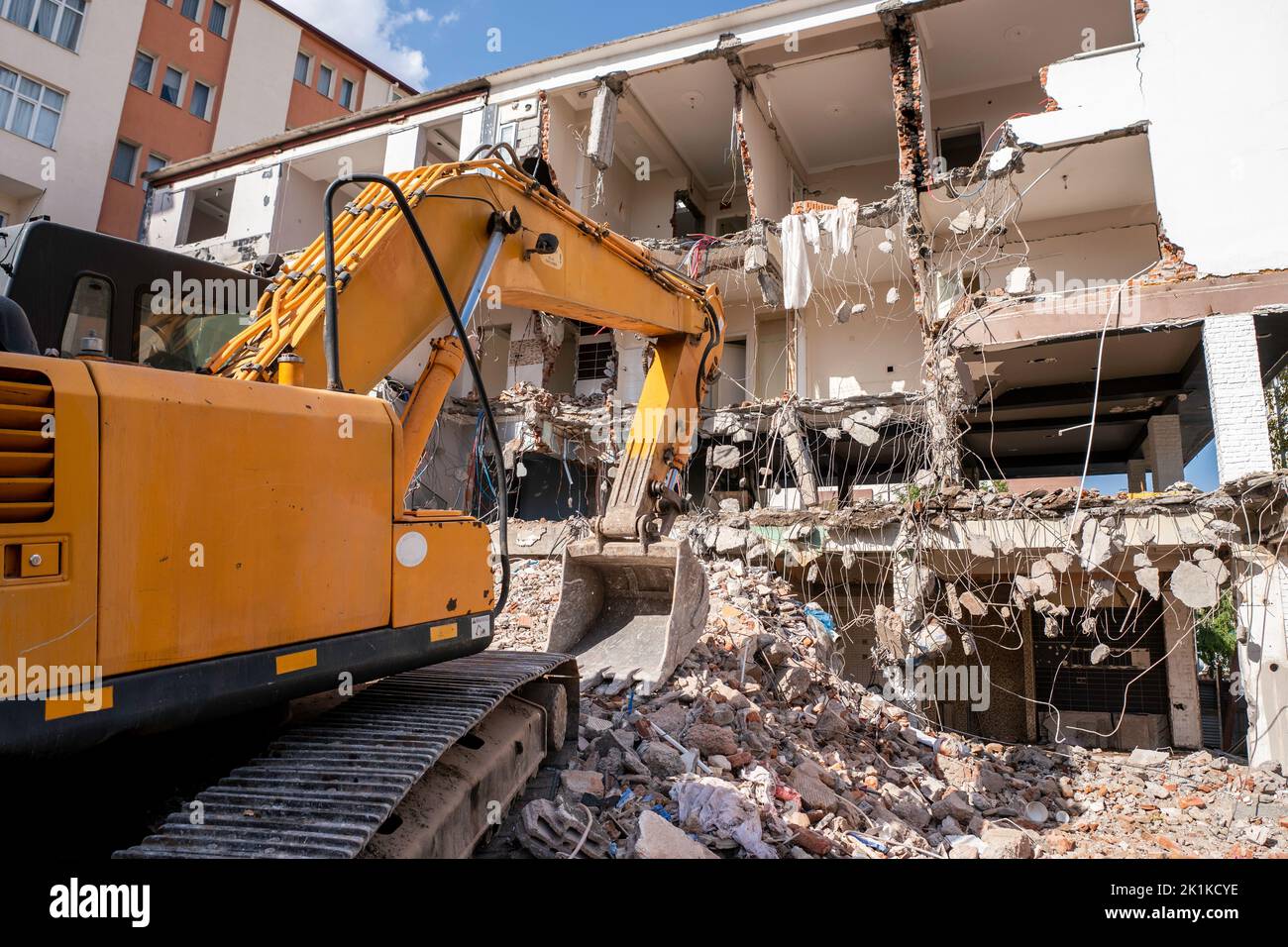 Una pesada máquina de trabajo industrial, digger está destruyendo un viejo edificio abandonado. Fotografía de alta calidad Foto de stock