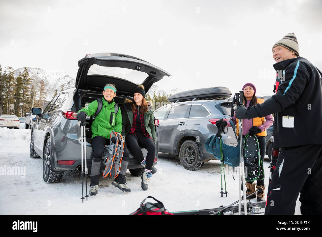 Parejas con equipo de esquí en coche exterior en el aparcamiento del complejo de esquí nevado Foto de stock