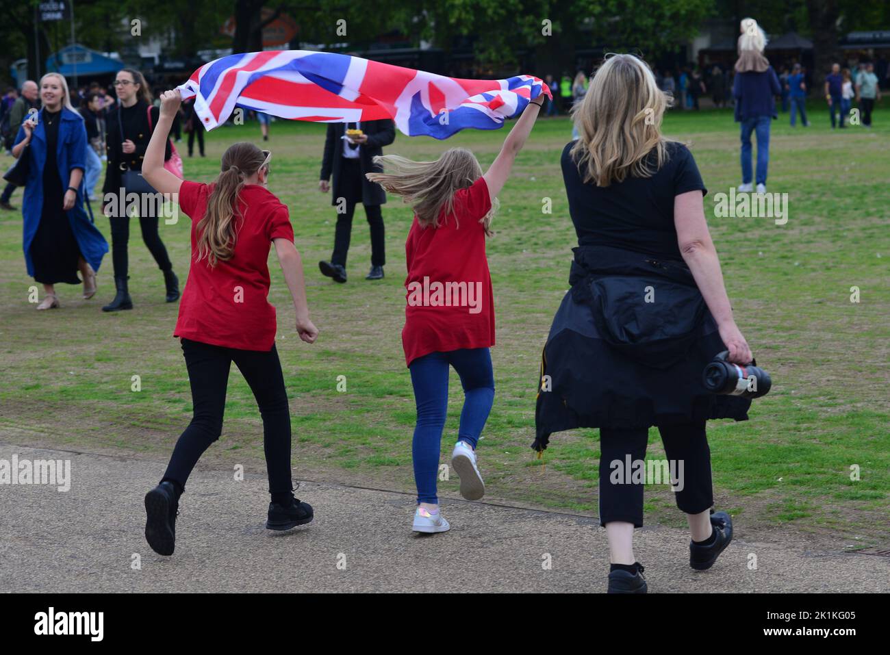 Funeral de Su Majestad la Reina Isabel II, Londres, Reino Unido, lunes 19th de septiembre de 2022. Dos chicas corriendo con la bandera de la Unión en Hyde Park. Foto de stock