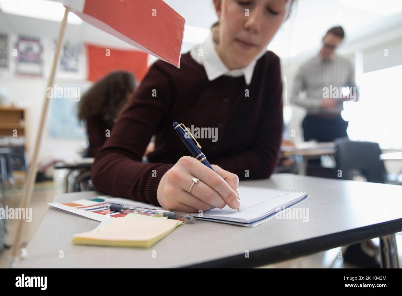 De cerca niña estudiante de la escuela secundaria escribiendo en el cuaderno en el escritorio Foto de stock