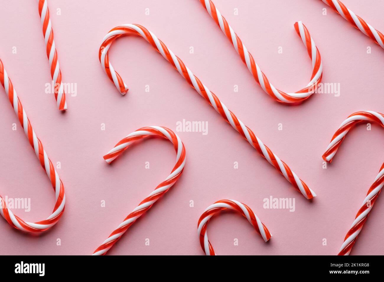 Patrón de bastón de caramelo con rayas duras sobre fondo rosa. Vacaciones de Navidad de fondo Foto de stock