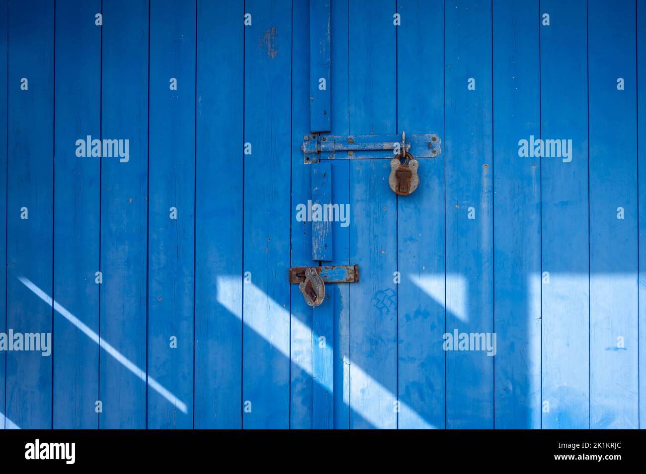 Puerta de madera azul con dos candados Foto de stock