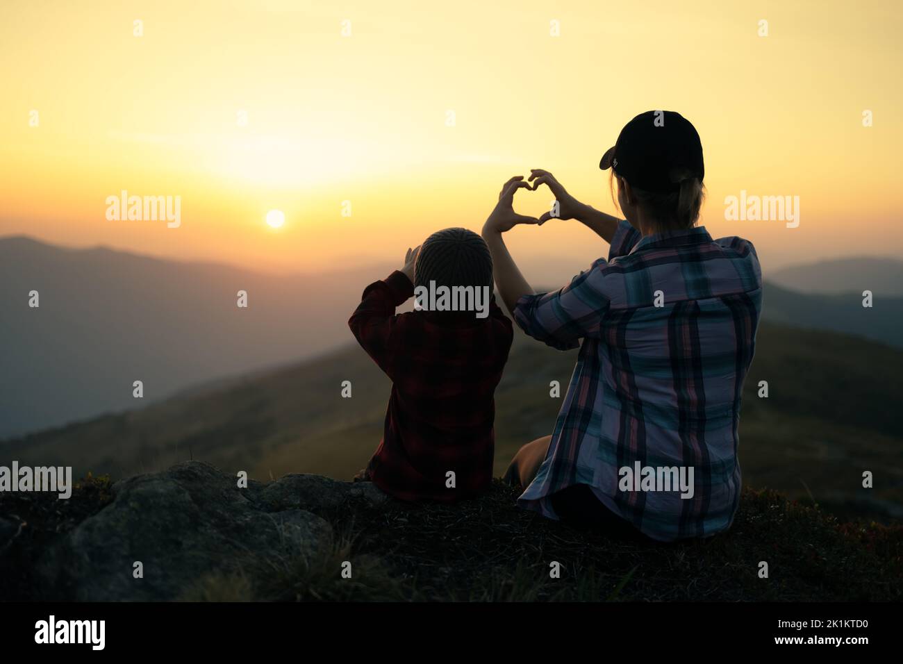 Mamá con su hijo en las montañas otoñales durante la puesta de sol. Viaje con concepto de niño Foto de stock