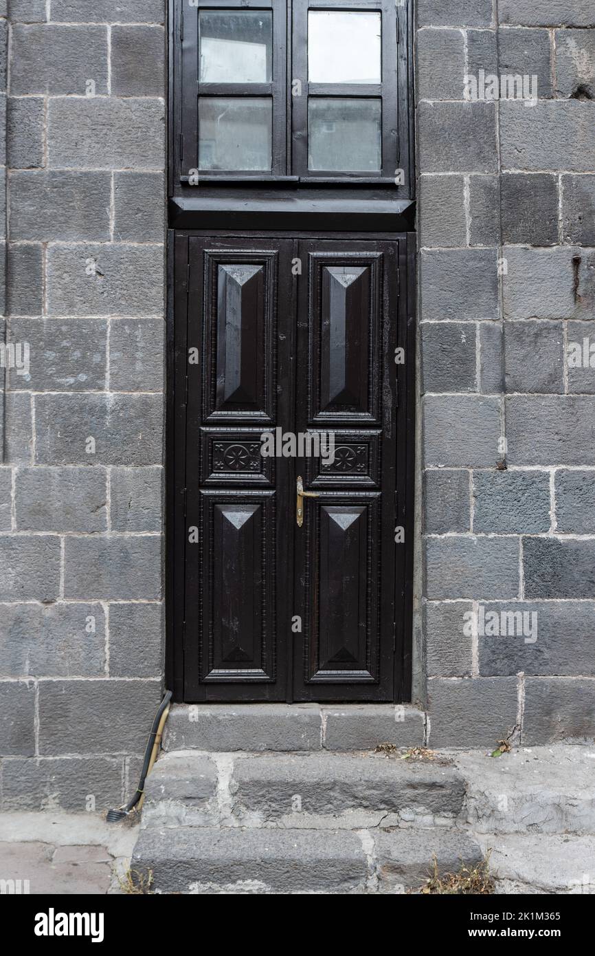Antigua casa de piedra clásica con puerta rústica de madera tallada en negro. Texturas de puerta y fondo. Fotografía de alta calidad Foto de stock