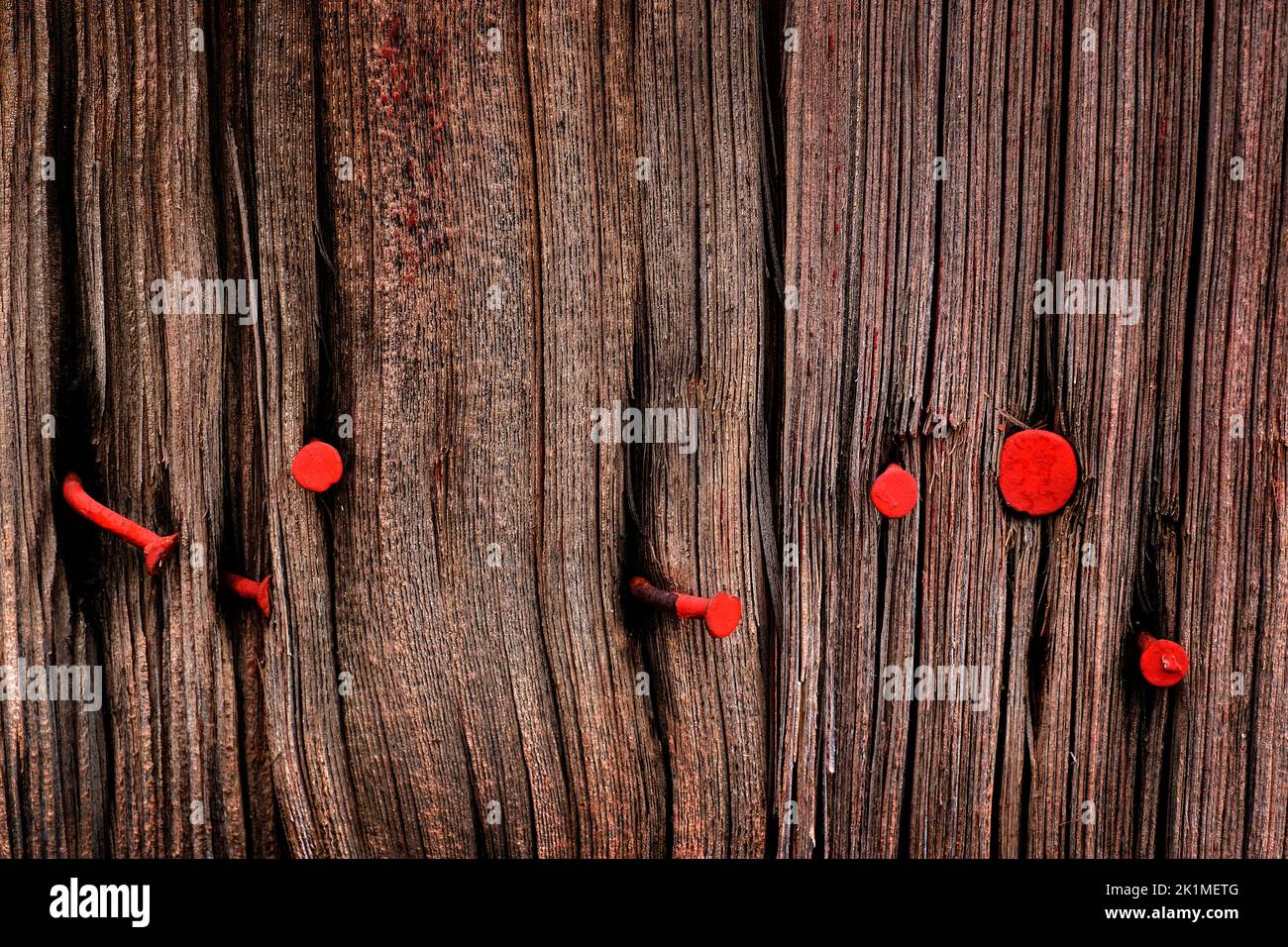 Detalle de la vieja pared de madera envejecida con ventanas y clavos de pintura roja Foto de stock