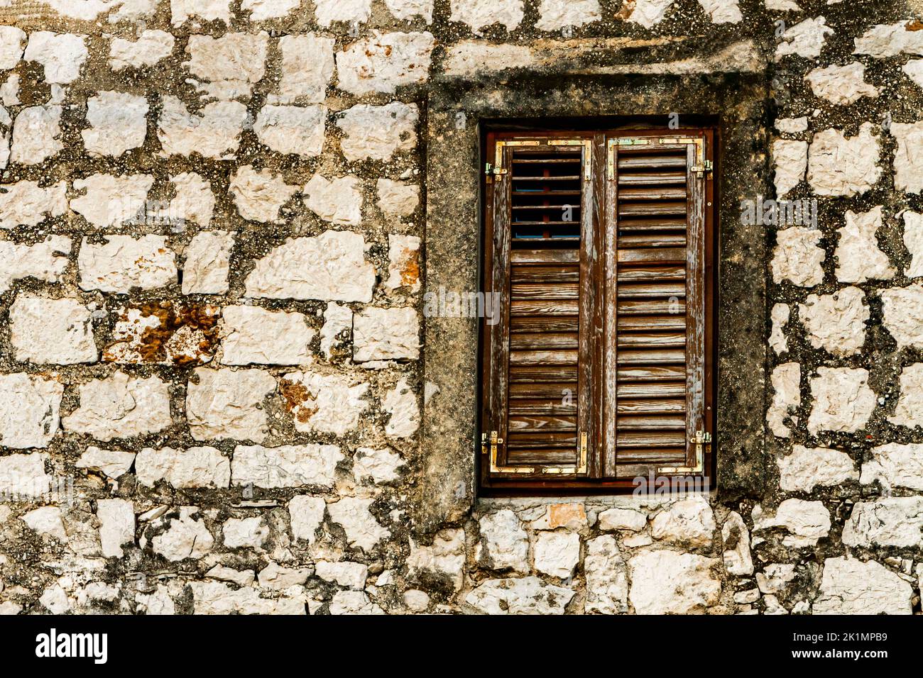 Detalle de la pared de piedra y la ventana con persianas de madera cerradas Foto de stock