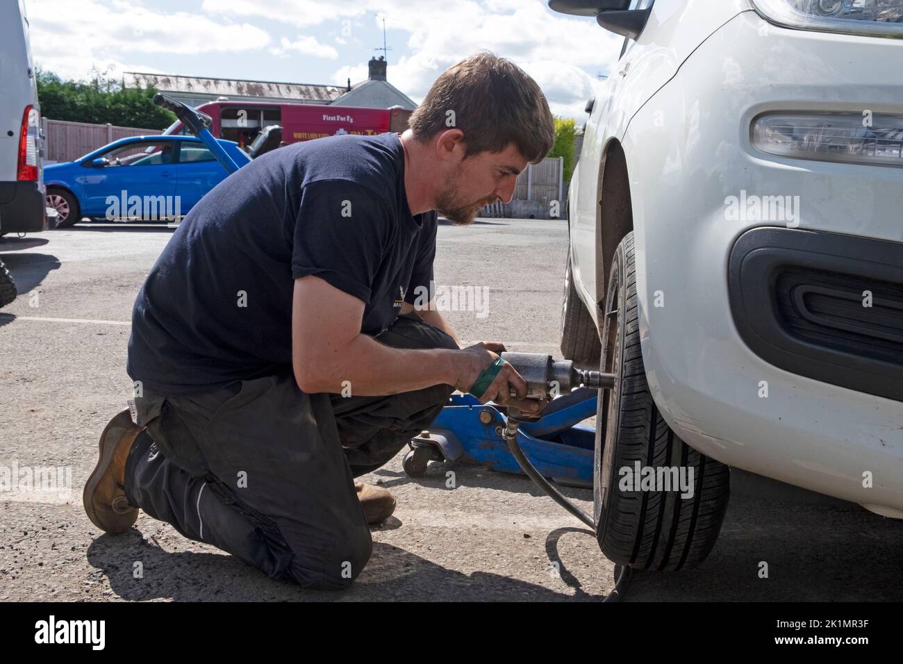 Joven trabajador mecánico de garaje Cambio de neumático en la rueda de un coche en Llandovery Wales Carmarthenshire UK KATHY DEWITT Foto de stock