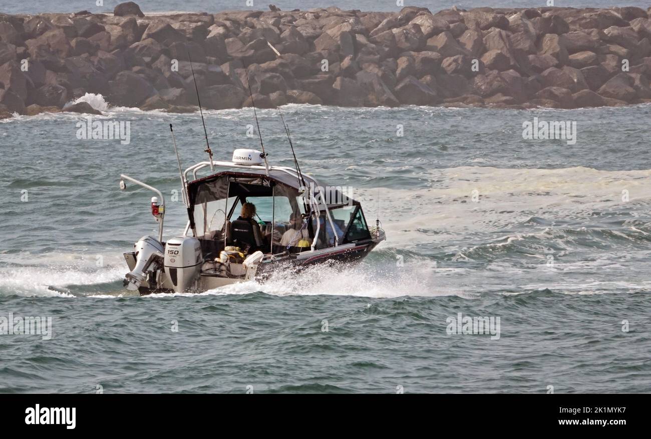 Un pequeño barco de pesca se dirige a ver a través del malecón de Florencia, Oregón y el Océano Pacífico. Foto de stock