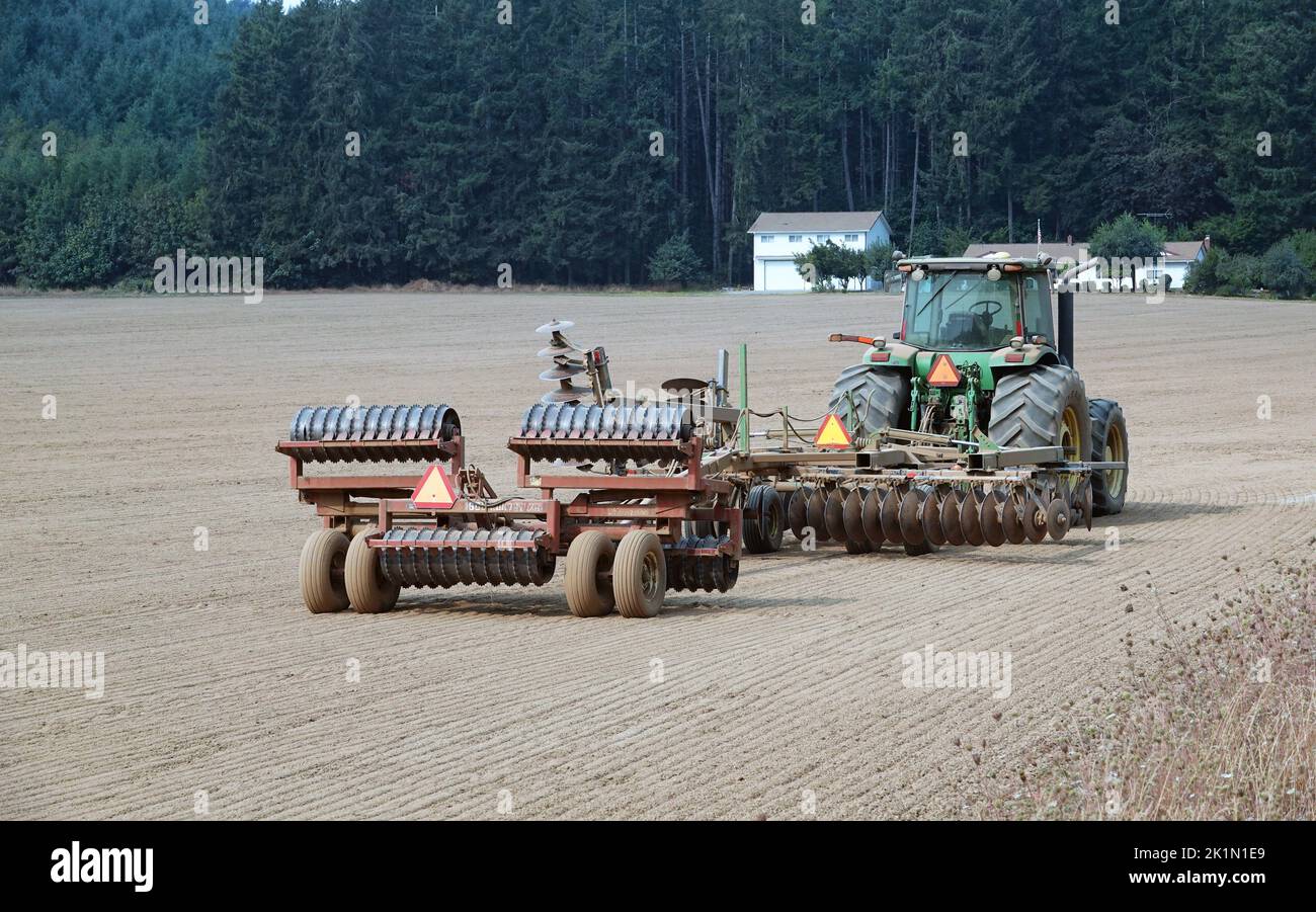 Un tractor agrícola y maquinaria de disco en un campo recién arado en las montañas Coast Range del oeste de Oregón. Foto de stock