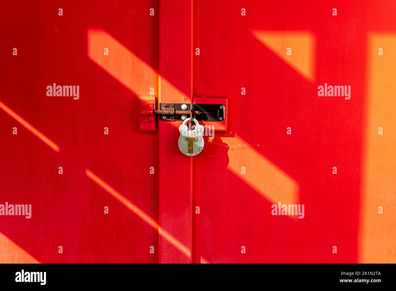 Puerta roja atornillada con candado. Foto de stock