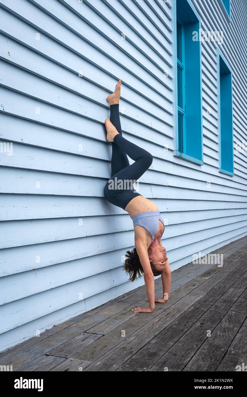 Mujer haciendo un soporte contra una pared de madera azul. Foto de stock