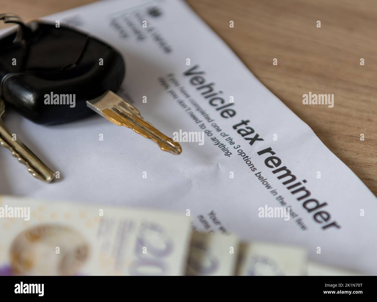 Un documento recordatorio de impuestos del vehículo de un escritorio con llaves del coche y dinero. Foto de stock
