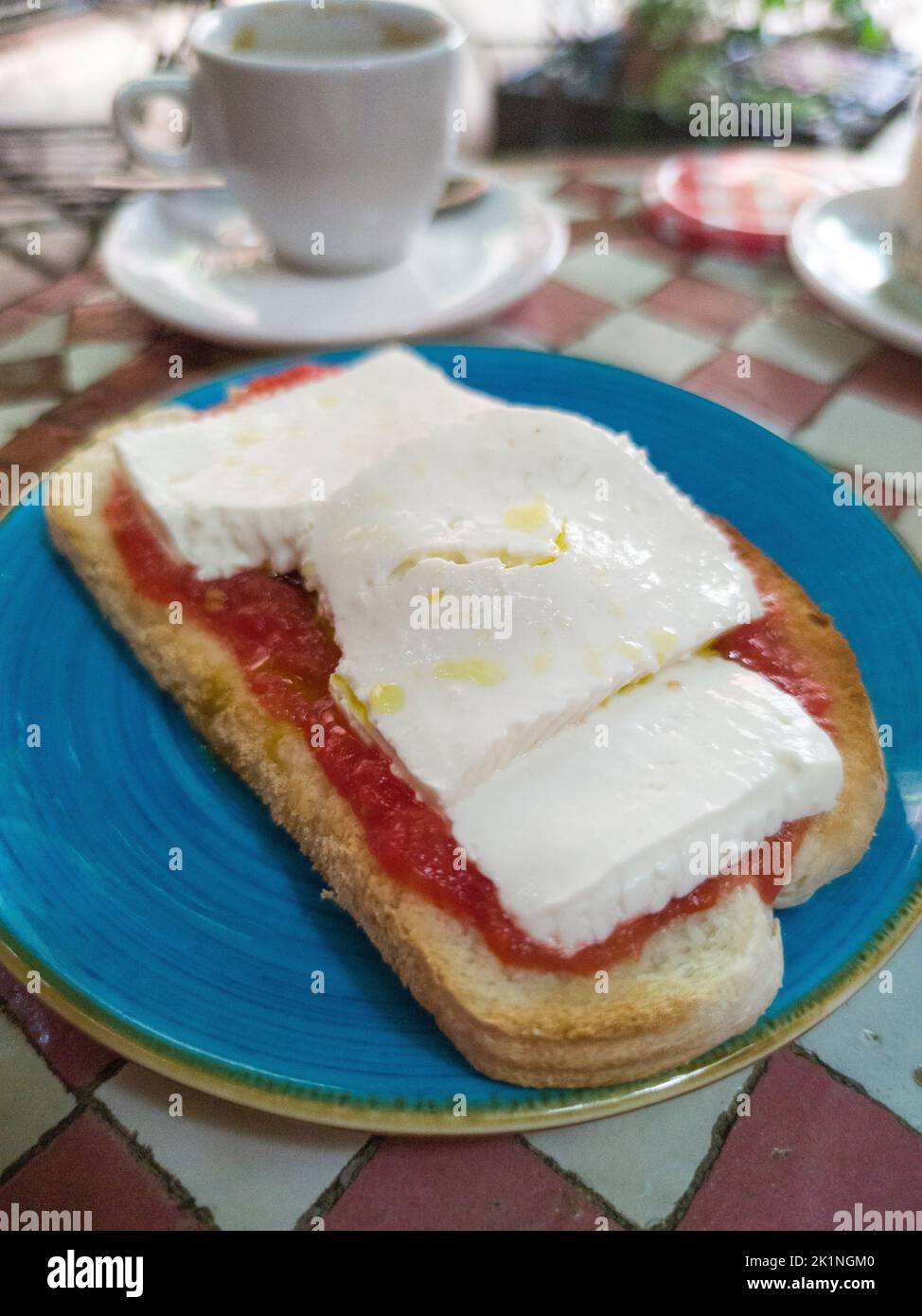 Pan tostado con queso cottage y tomate sobre una mesa de mosaico vidriado. Fondo de estilo árabe Foto de stock