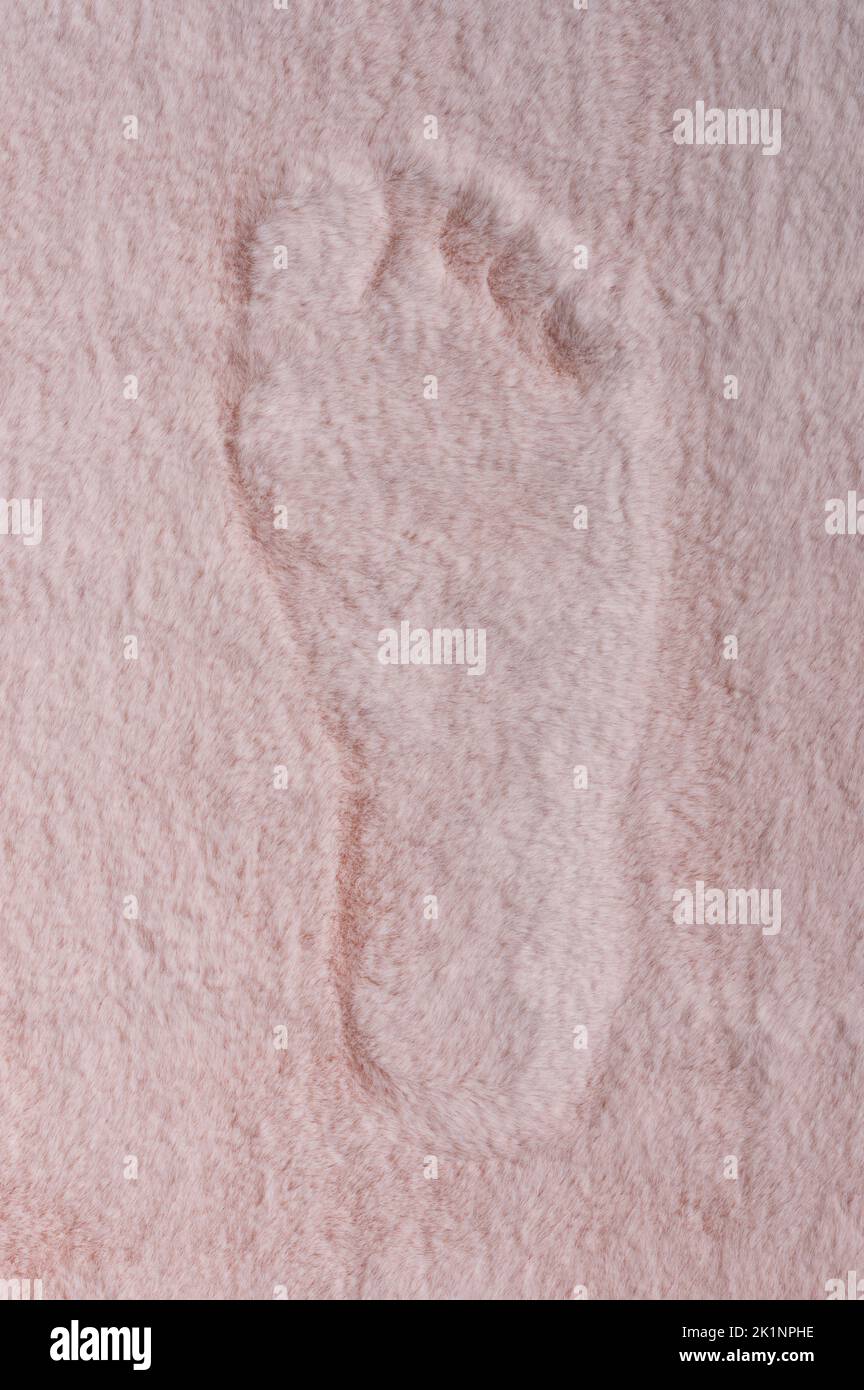 Vista de primer plano de una alfombra rosa suave con pie descalzo Foto de stock
