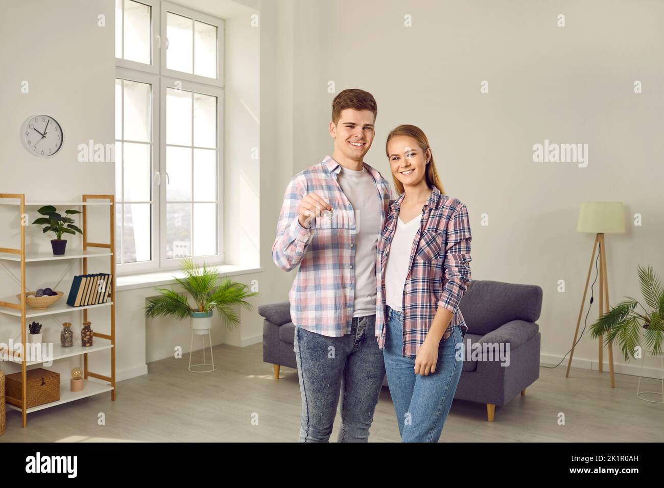 Retrato de una joven familia feliz con llaves en el salón de su nueva casa Foto de stock