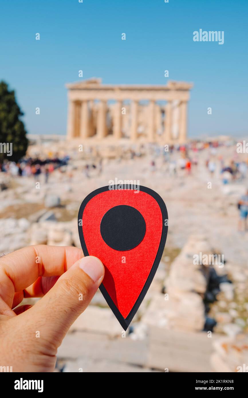 Primer plano de un hombre sosteniendo un marcador rojo señalando los restos del famoso Partenón, en la Acrópolis de Atenas, Grecia, en un día soleado Foto de stock