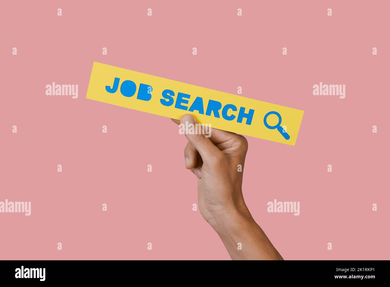 el hombre sostiene un letrero de papel amarillo con el texto de búsqueda de trabajo en él, sobre un fondo rosa Foto de stock