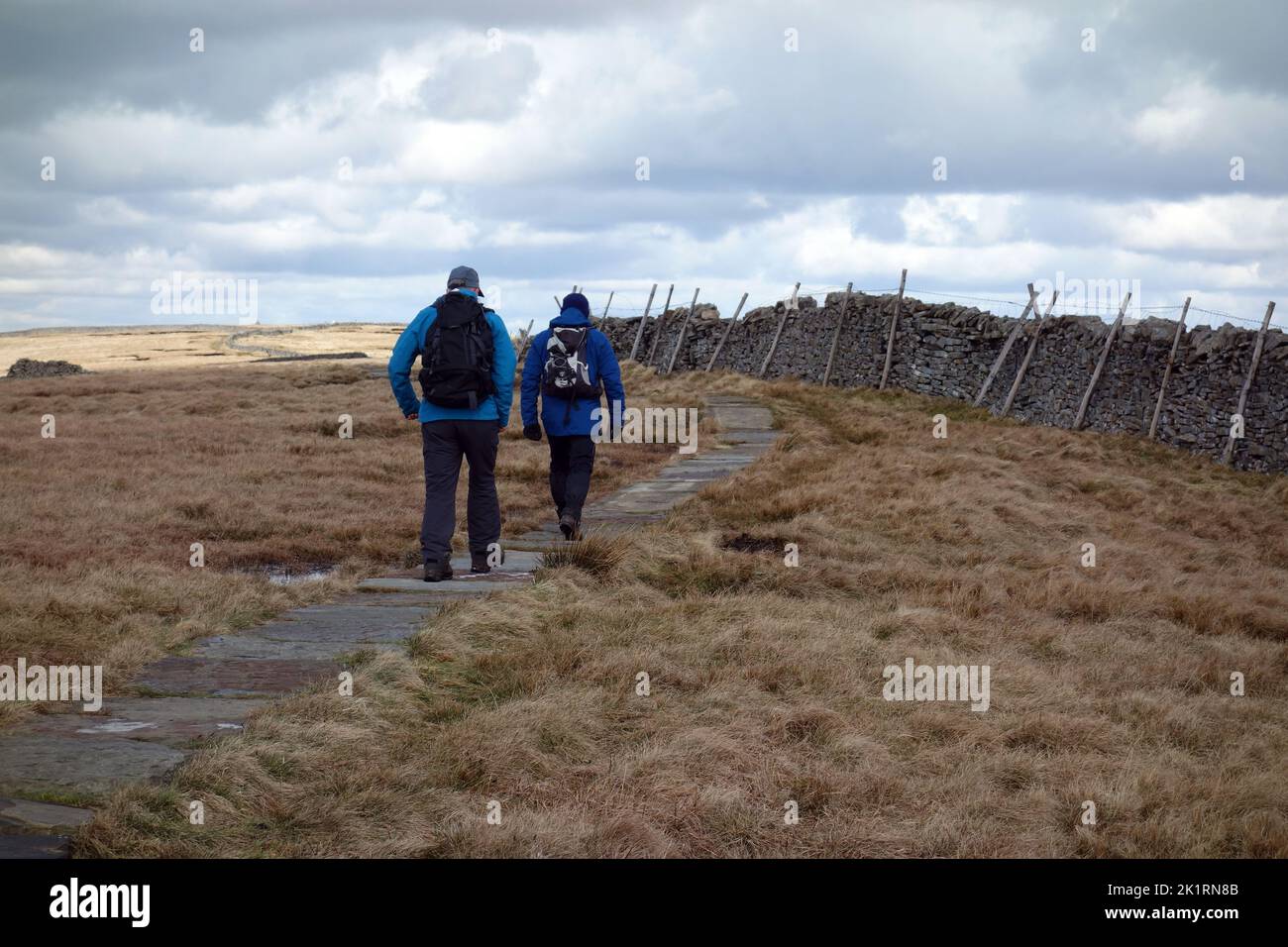 Dos hombres caminando por la pared de piedra seca hasta la cumbre de Buckden Pike en el Parque Nacional Yorkshire Dales, Inglaterra, Reino Unido. Foto de stock