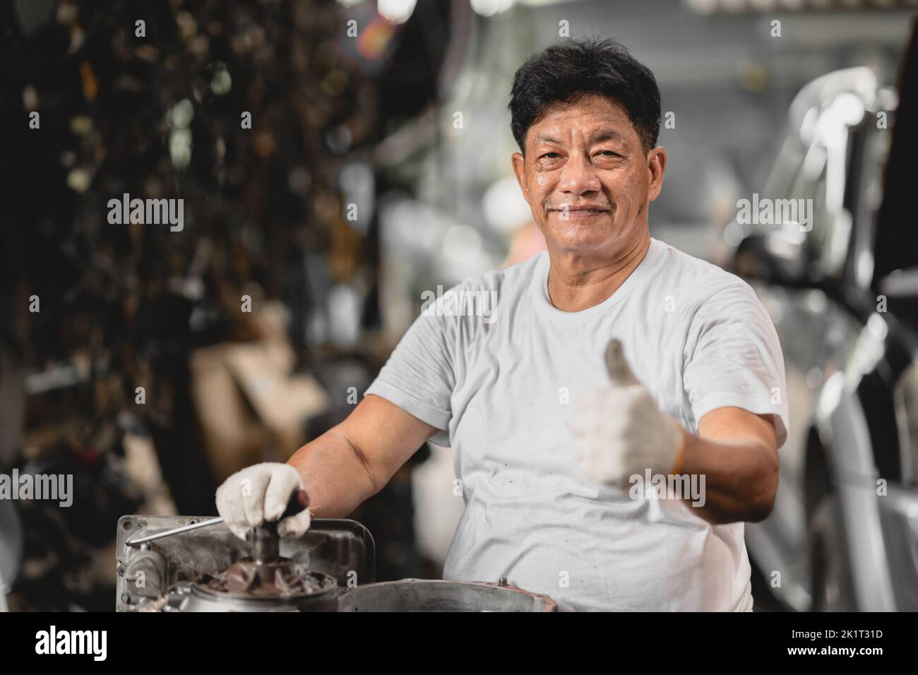 feliz asiático hombre adulto trabajador pulgares para arriba buen trabajo disfrutar de trabajar en el garaje Foto de stock