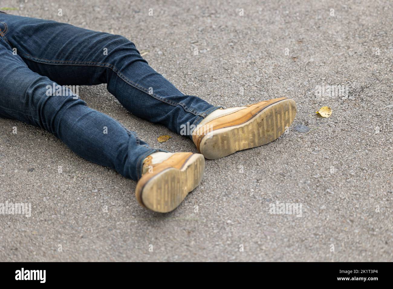 primer plano de la pierna masculina tumbada en carretera asfaltada. peatón atropellado por el concepto de accidente de coche. Foto de stock