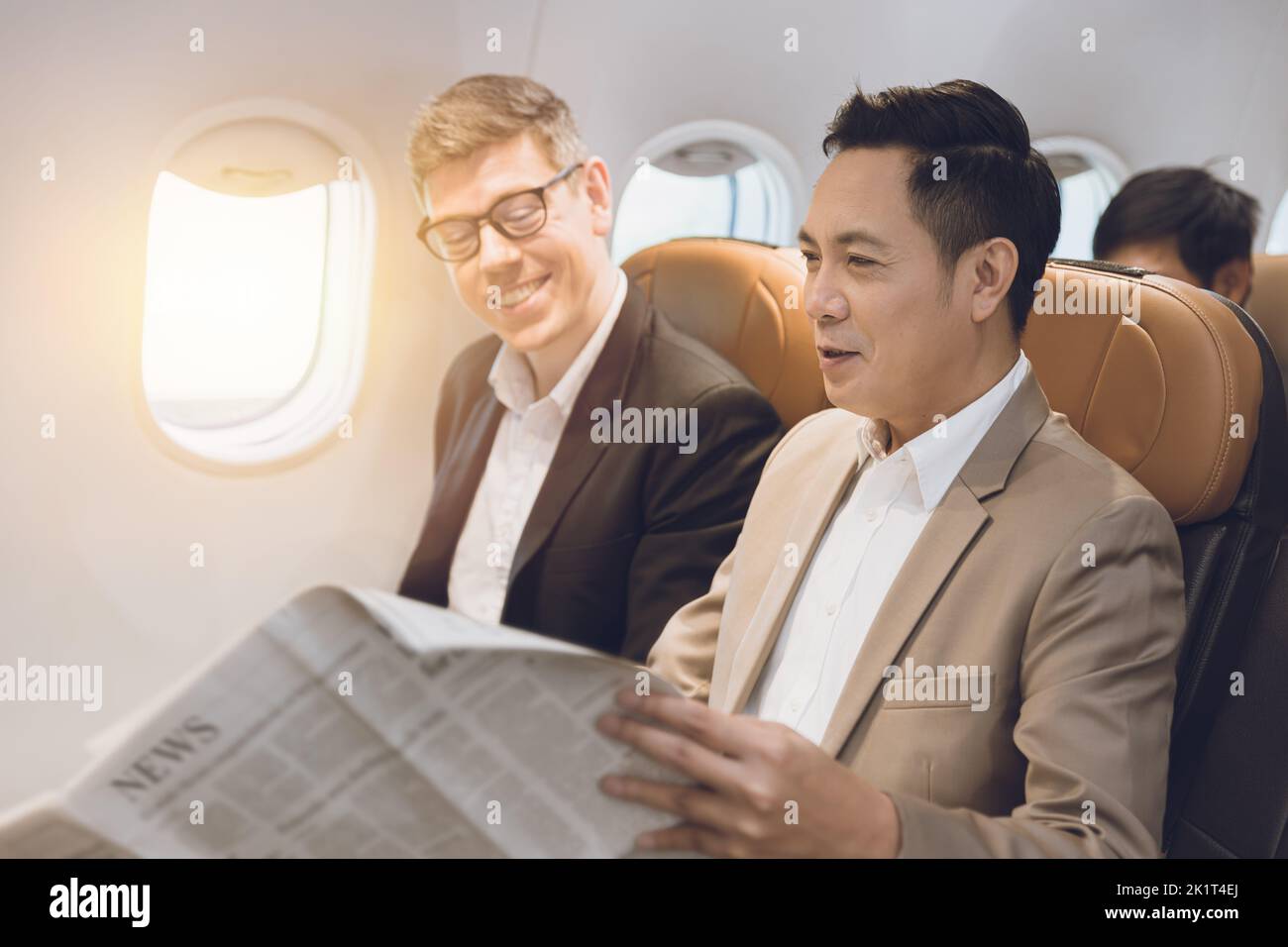 dos hombres de negocios en la cabina de vuelo hablando juntos sobre el artículo de noticias en el periódico happy smile Foto de stock