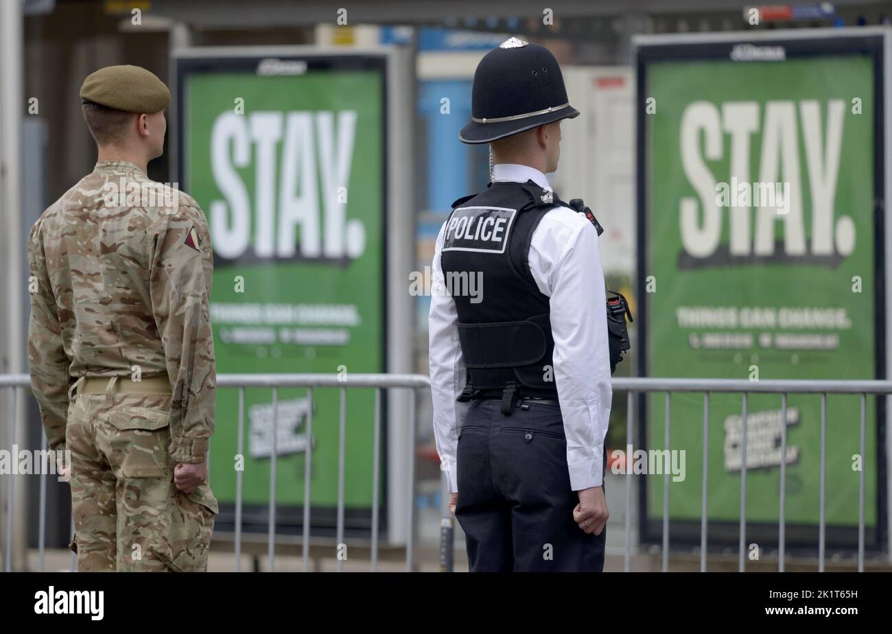 Londres, Reino Unido. El día del Funeral del Estado de la Reina Isabel II Un soldado y un oficial de policía de pie a la atención frente a 'estancia' ad hoardings Foto de stock