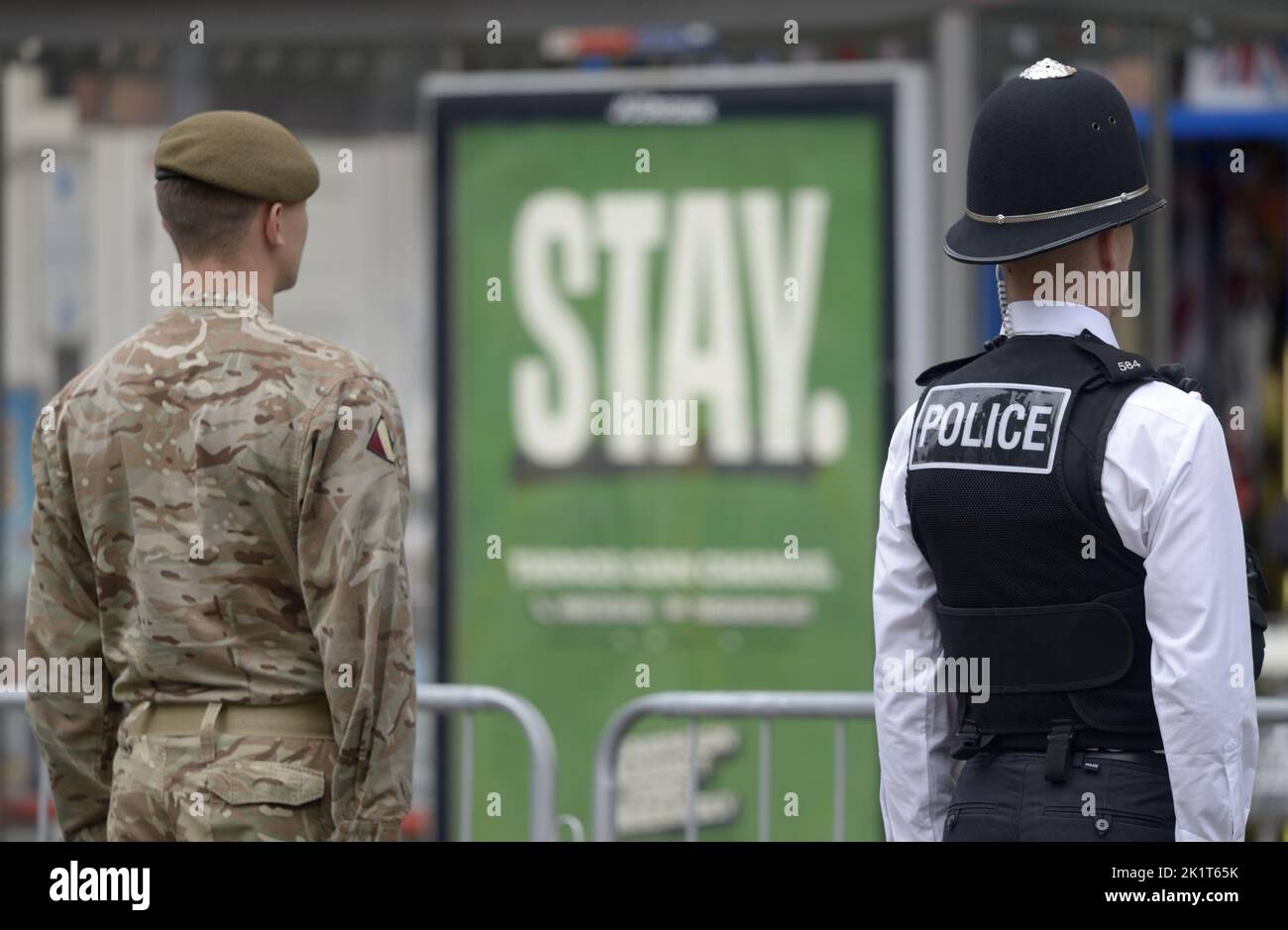 Londres, Reino Unido. El día del Funeral del Estado de la Reina Isabel II Un soldado y un oficial de policía de pie a la atención frente a 'estancia' ad hoardings Foto de stock