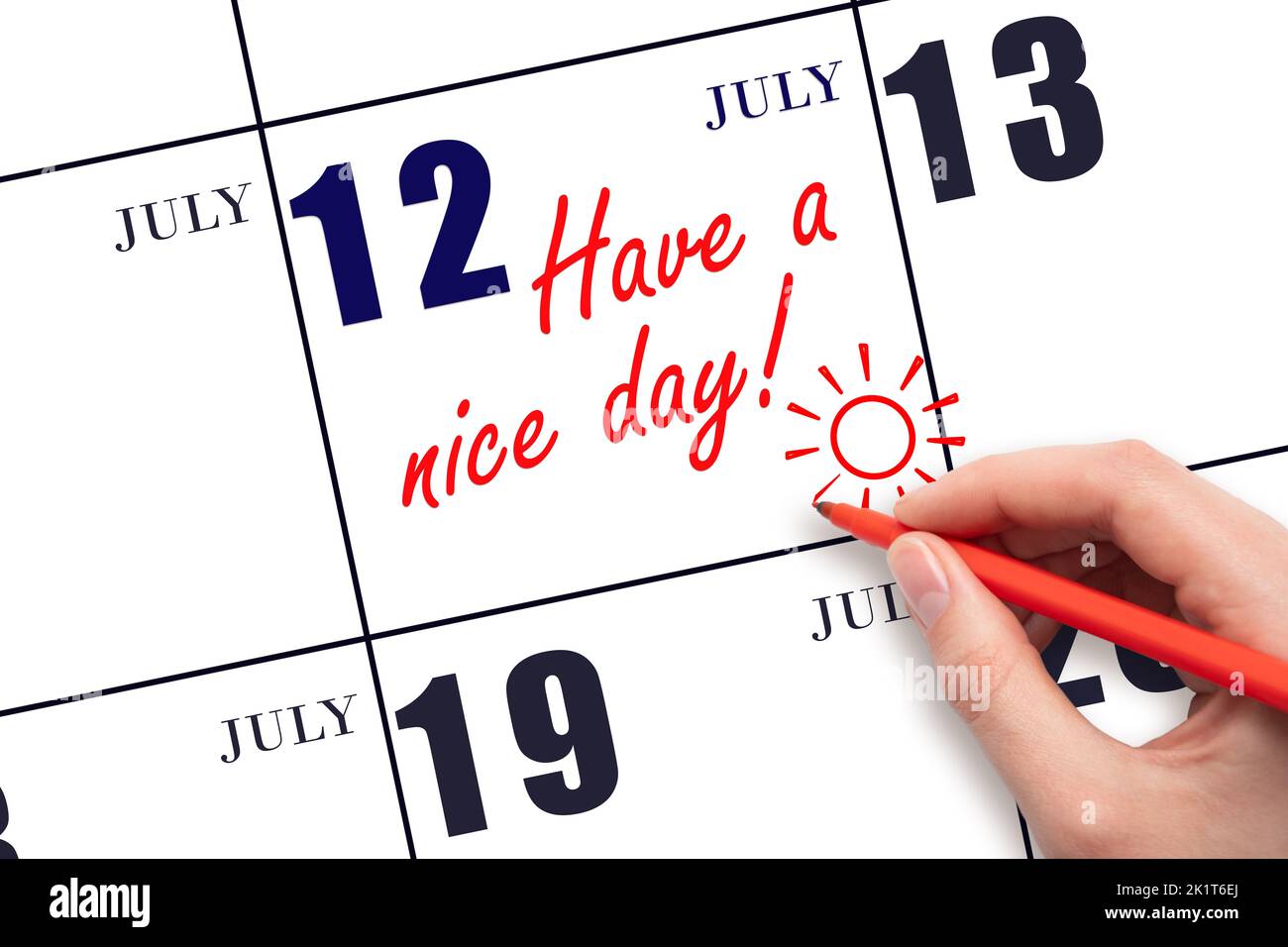 12th día de julio. La mano que escribe el texto tienen un día agradable y dibujar el sol en la fecha del calendario 12 de julio. Guarde la fecha. Mes de verano, día del Foto de stock