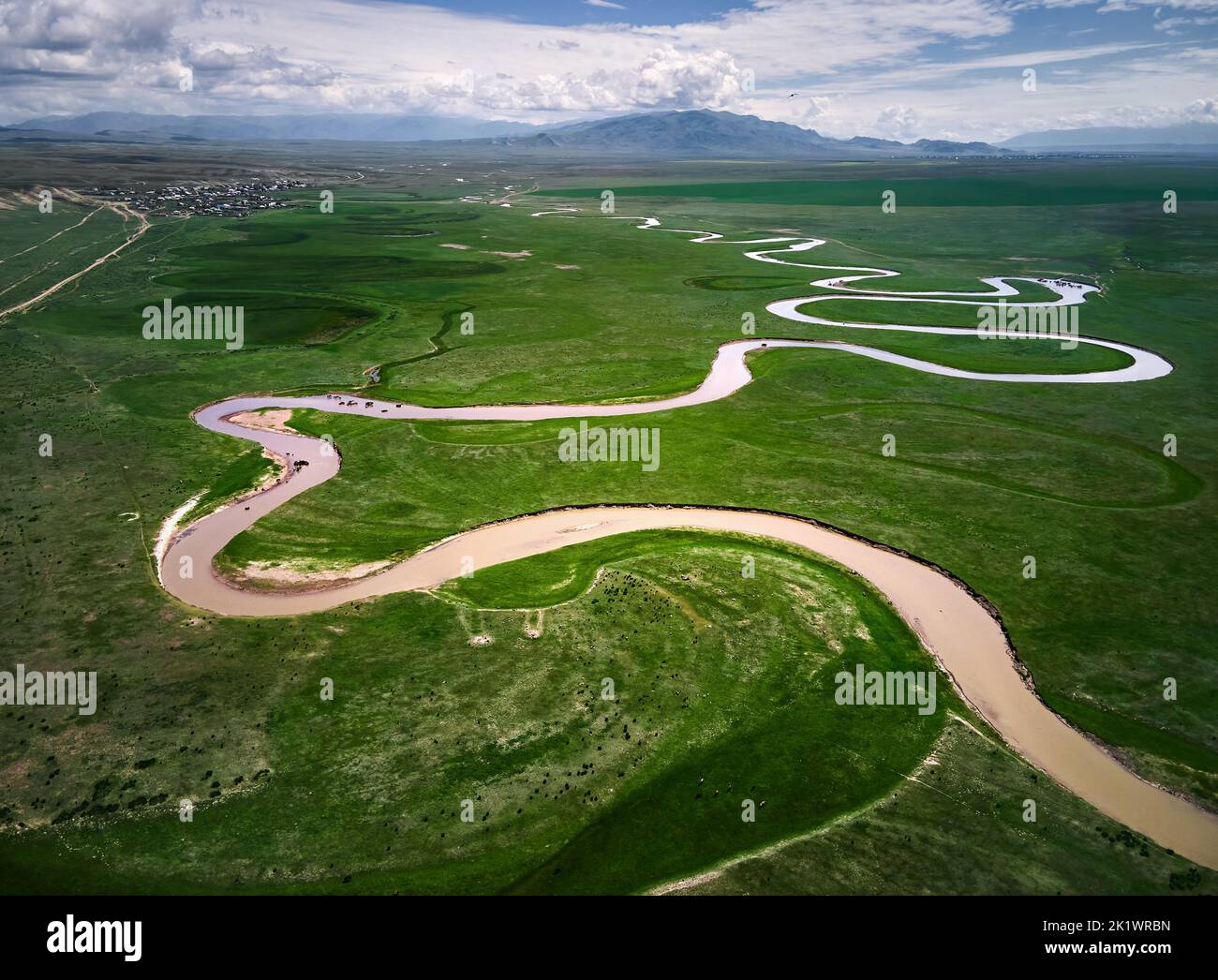 Plano aéreo del drone del río de curva hermoso paisaje de Kegen con colinas verdes en el resplandor de la luz del atardecer en el valle de la montaña, Kazakhstan. Manada de alimentación de caballos i Foto de stock