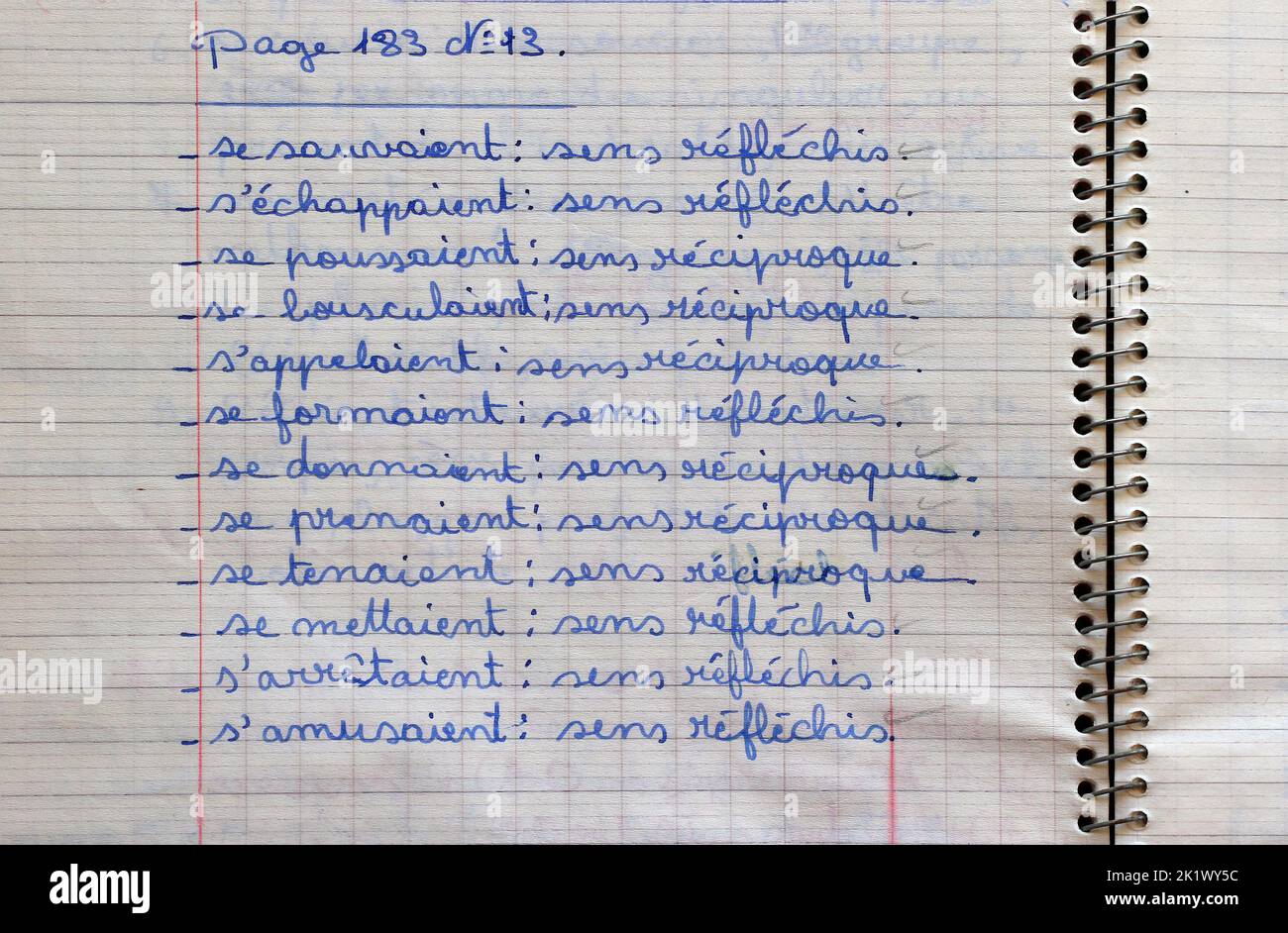 Un cuaderno de la escuela de color amarillo con una tarea de gramática en francés. Foto de stock