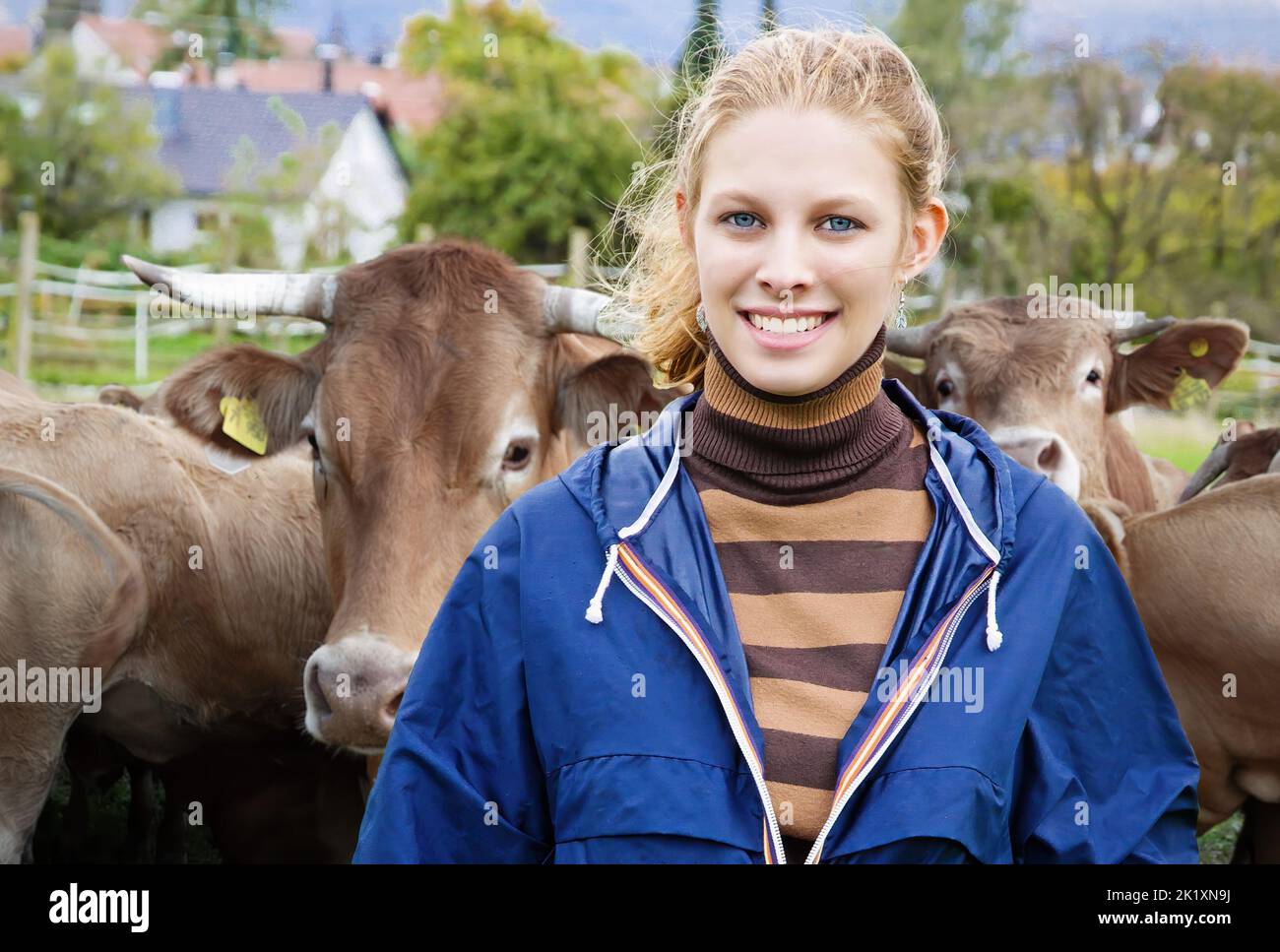 Joven Mujer granja en el paddock, en un hato de ganado de fondo Foto de stock