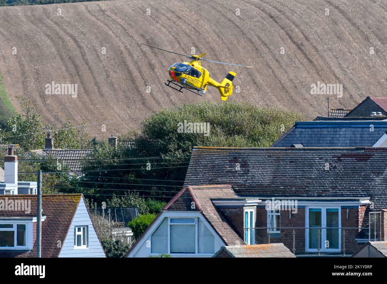 Burton Bradstock, Dorset, Reino Unido, 21st de septiembre de 2022. Un helicóptero de electricidad amarillo volando bajo sobre líneas eléctricas comprobando si hay fallos cerca de las casas de Burton Bradstock en Dorset. Crédito de la imagen: Graham Hunt/Alamy Live News Foto de stock