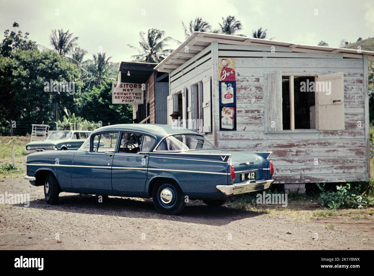 Coches estacionados fuera de los edificios de la terminal del puerto aéreo, St Vincent, Windward Islands, West Indies, 1962 Vauxhall Velox car Foto de stock