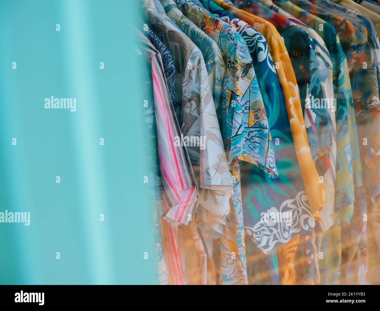 Camisas de surf de verano coloridas de estilo hawaiano vintage en un estante en una tienda de ropa retro de verano. Foto de stock