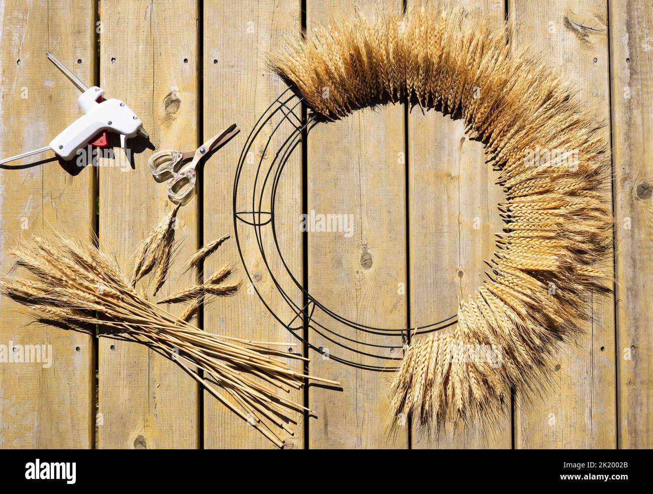 Corona de puerta de trigo con pegamento caliente y tijeras Foto de stock