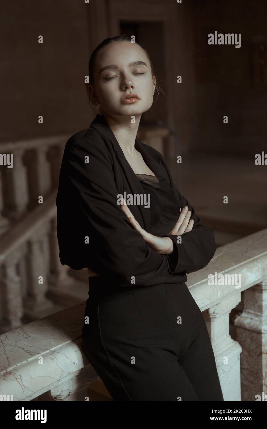 Retrato de una niña en una chaqueta negra clásica con ojos cerrados Foto de stock