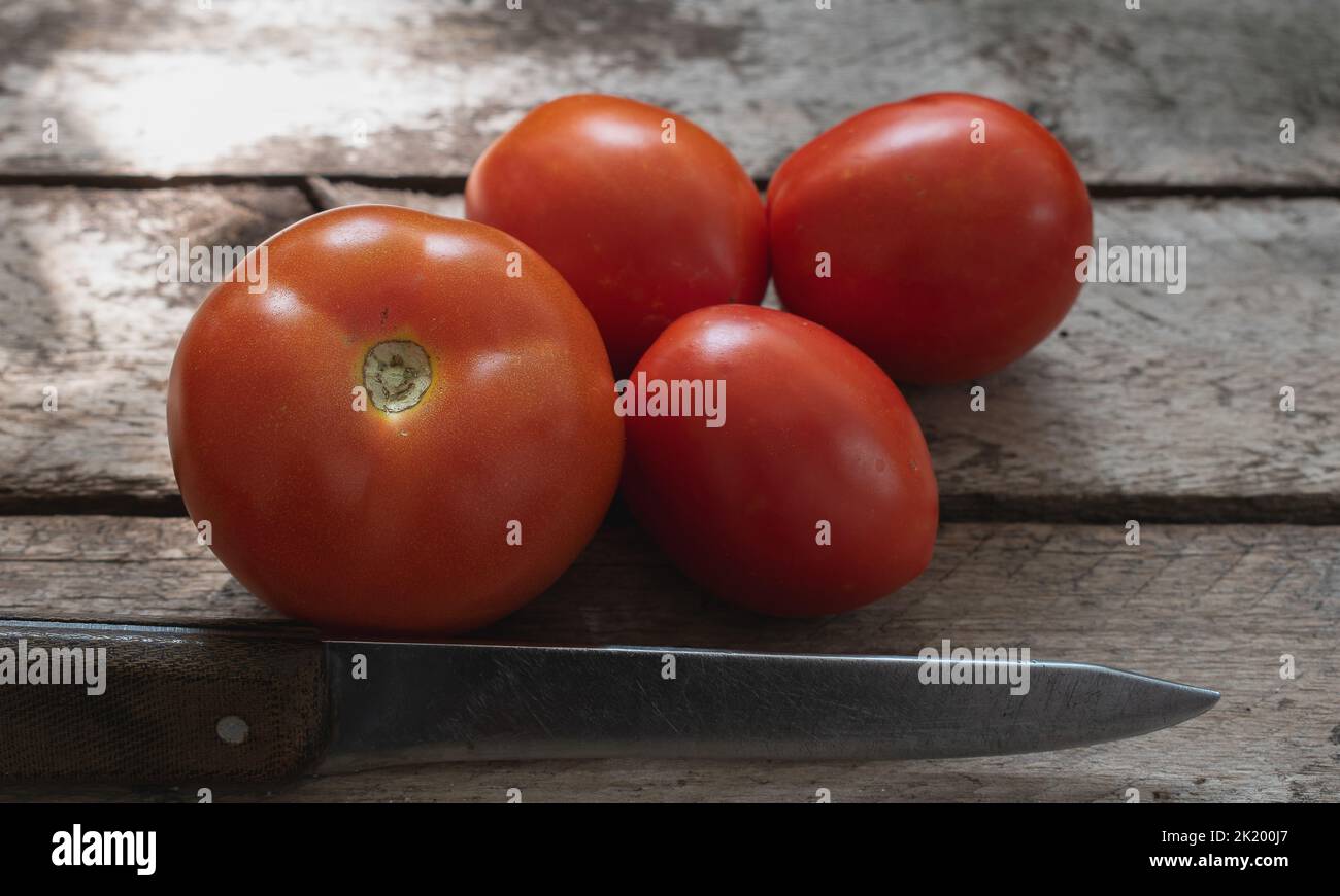 Primer plano de tomates rojos sobre una mesa de madera. Foto de stock
