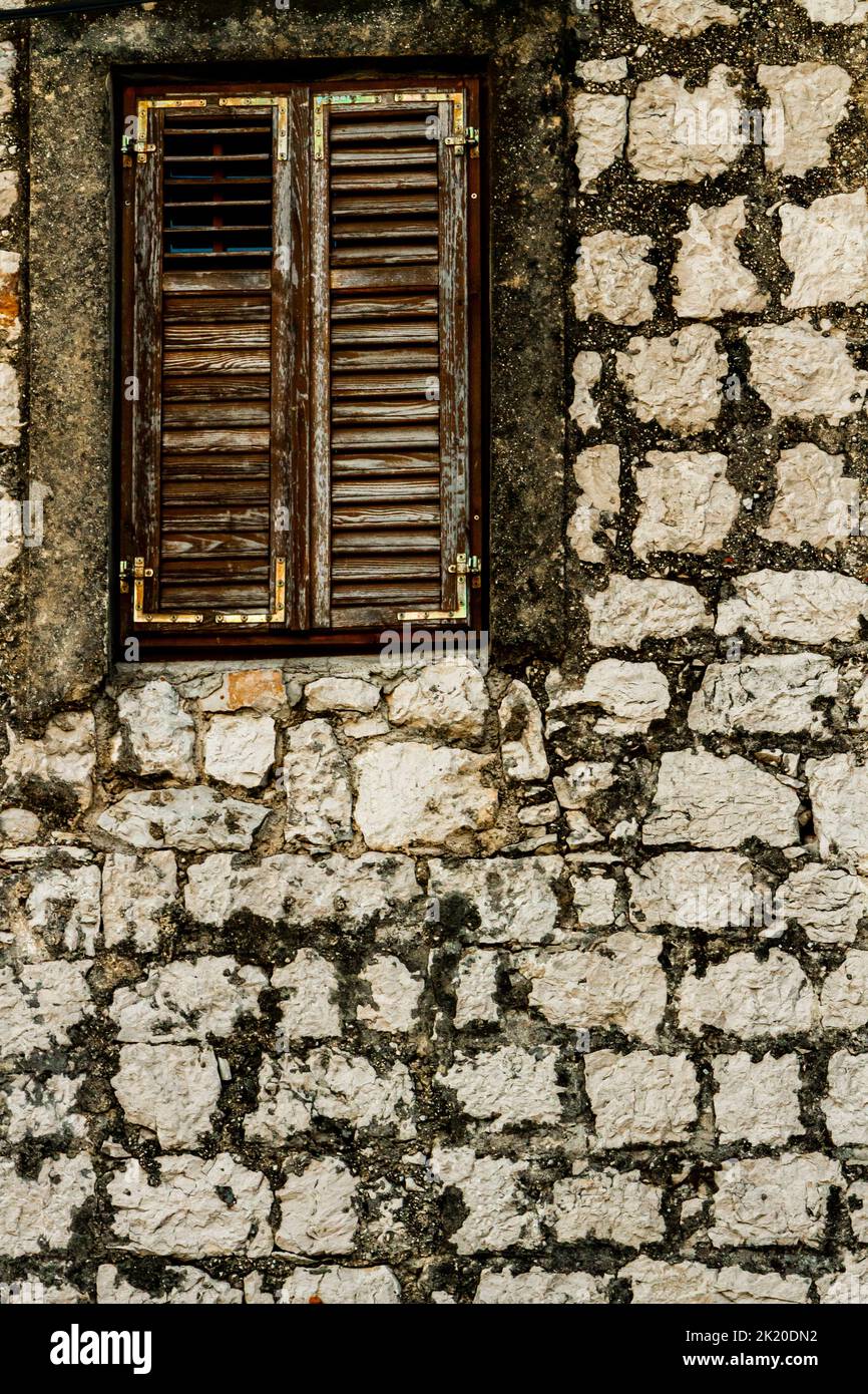 Detalle de la pared de piedra y la ventana con persianas de madera cerradas Foto de stock