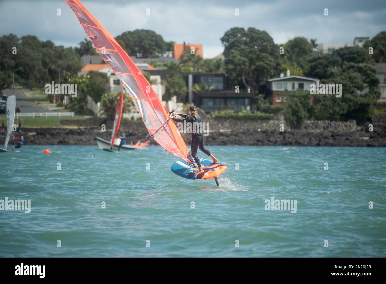 Un hombre compite en una carrera nacional de hidroala de windsurf en el Waterbourne Watersports Festival, Takapuna Beach, Auckland, Nueva Zelanda. Foto de stock