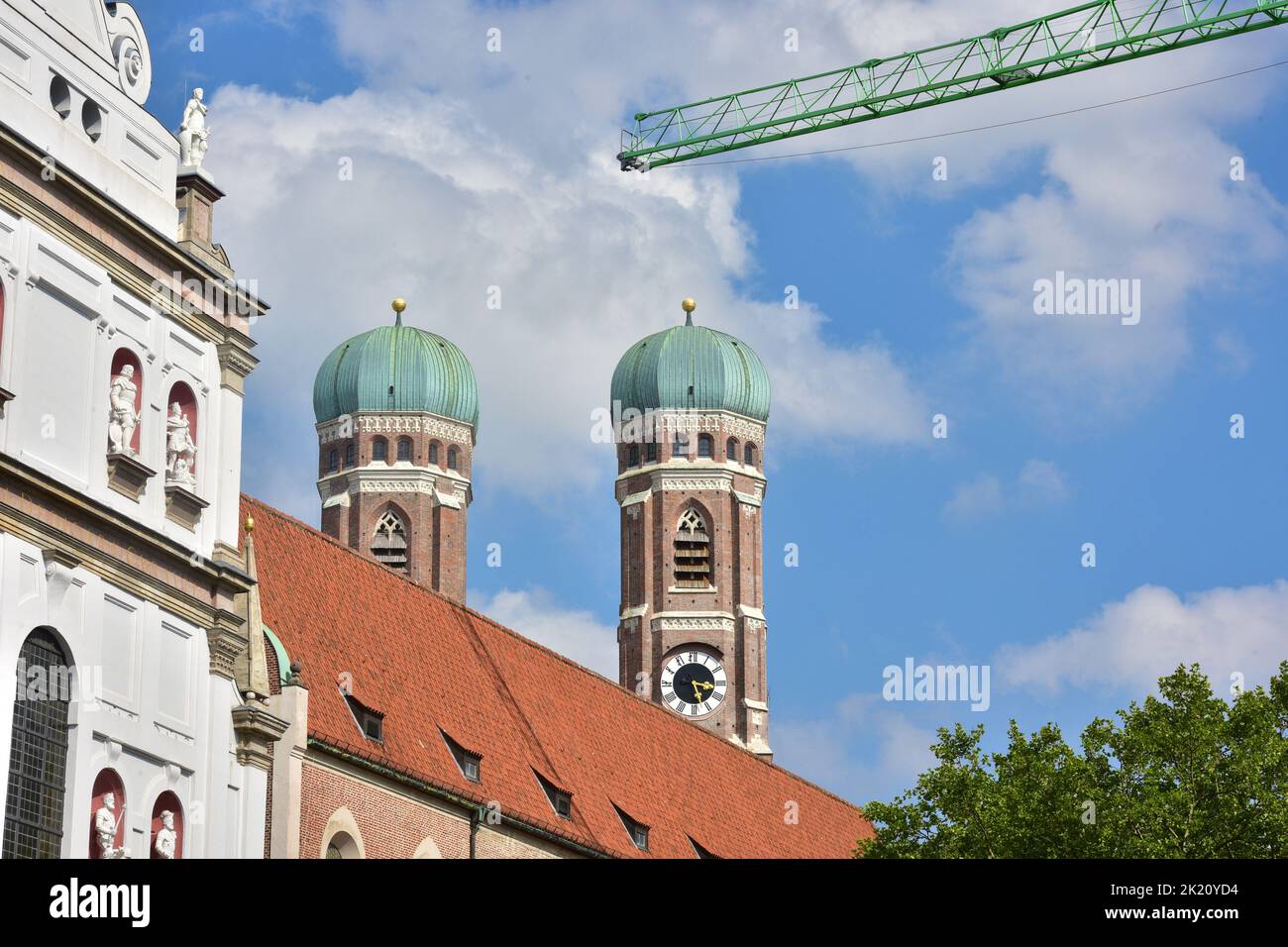La Frauenkirche en Munich con el cielo azul y la grúa de construcción en primer plano Foto de stock
