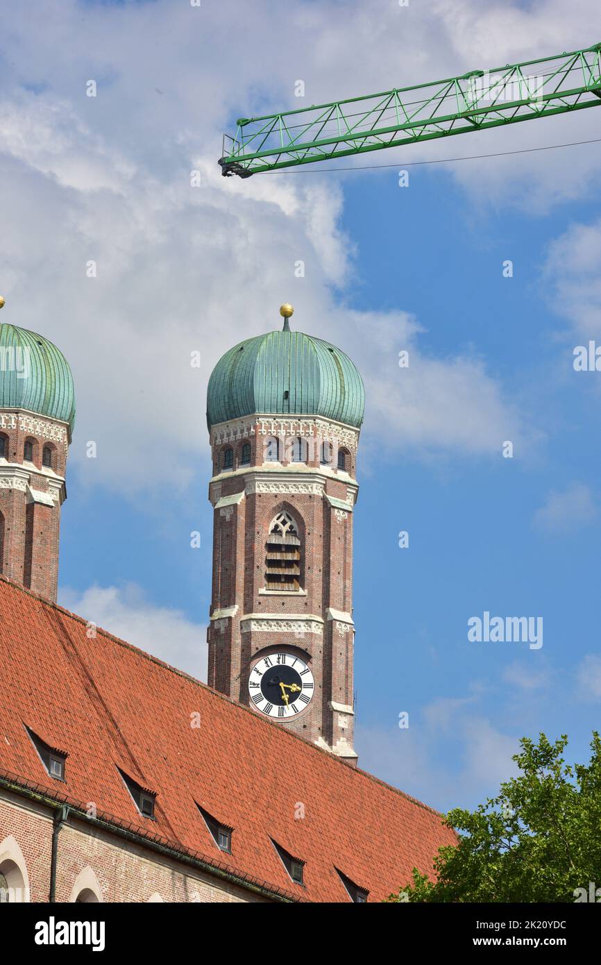 La Frauenkirche en Munich con el cielo azul y la grúa de construcción en primer plano Foto de stock