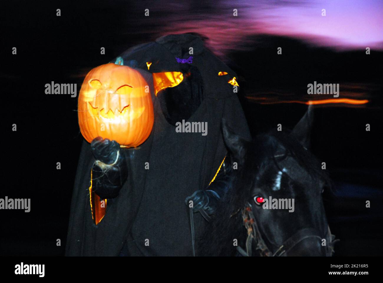 El jinete sin cabeza levanta una cabeza de calabaza al anochecer de otoño en un festival de otoño en Sleepy Hollow, cerca de Halloween celebrando la historia de Washington Irving Foto de stock