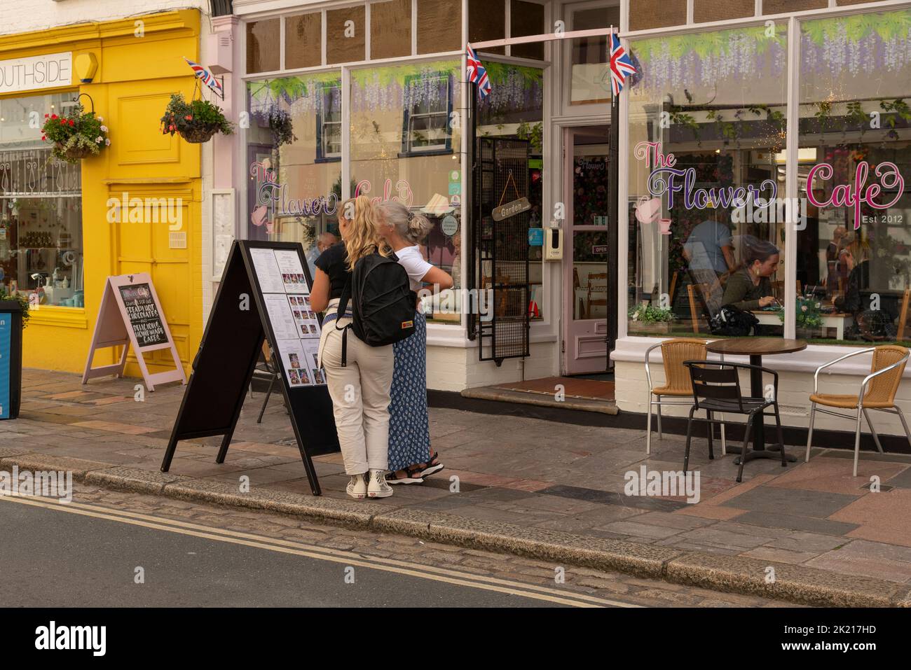Plymouth, Devon, Inglaterra, Reino Unido. 2022. Mujeres leyendo un menú en el pavimento fuera de un café en la zona de Brabican de la ciudad. Plymouth, Inglaterra. Foto de stock