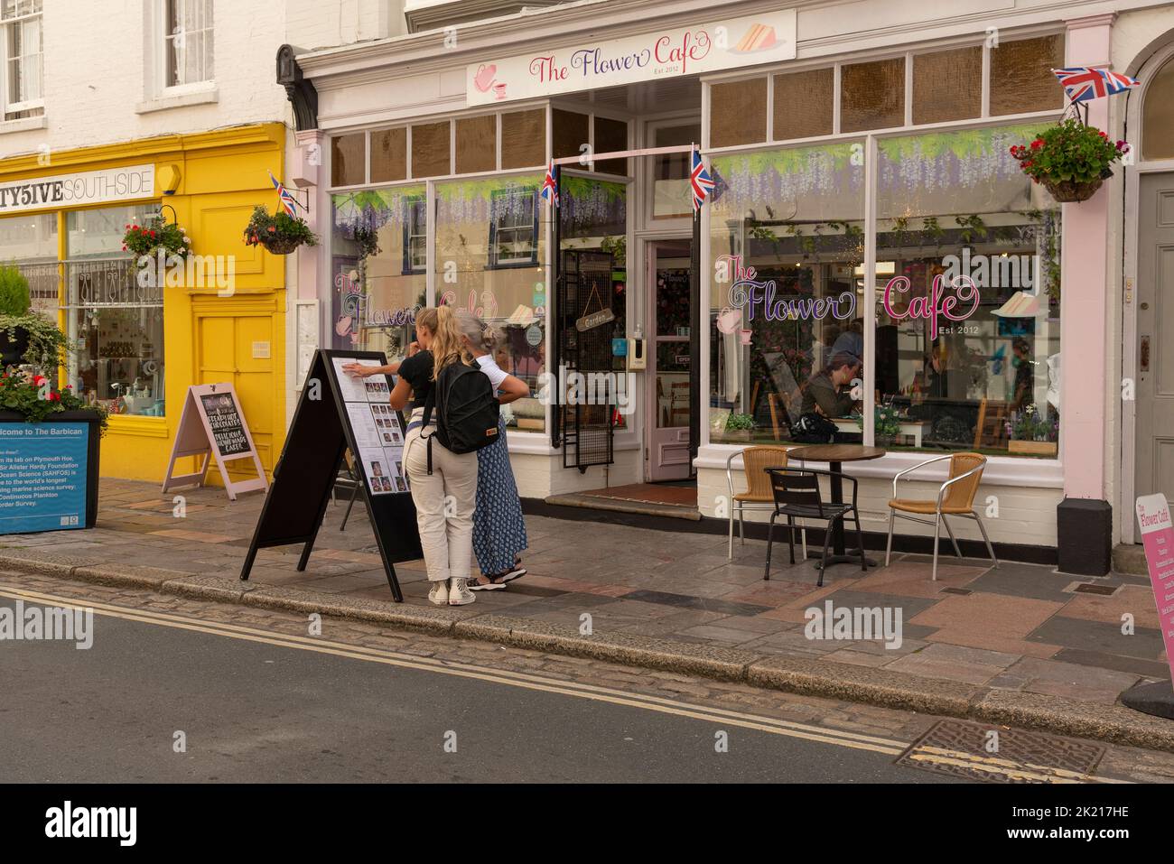 Plymouth, Devon, Inglaterra, Reino Unido. 2022. Mujeres leyendo un menú en el pavimento fuera de un café en la zona de Brabican de la ciudad. Plymouth, Inglaterra. Foto de stock