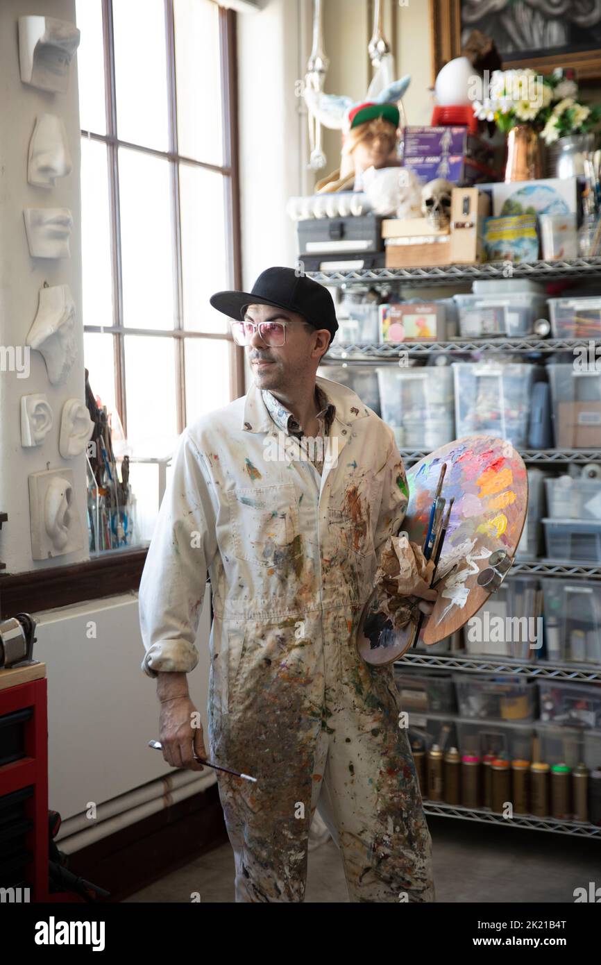 Artista masculino en overoles con una paleta de pintura en un estudio de  arte Fotografía de stock - Alamy