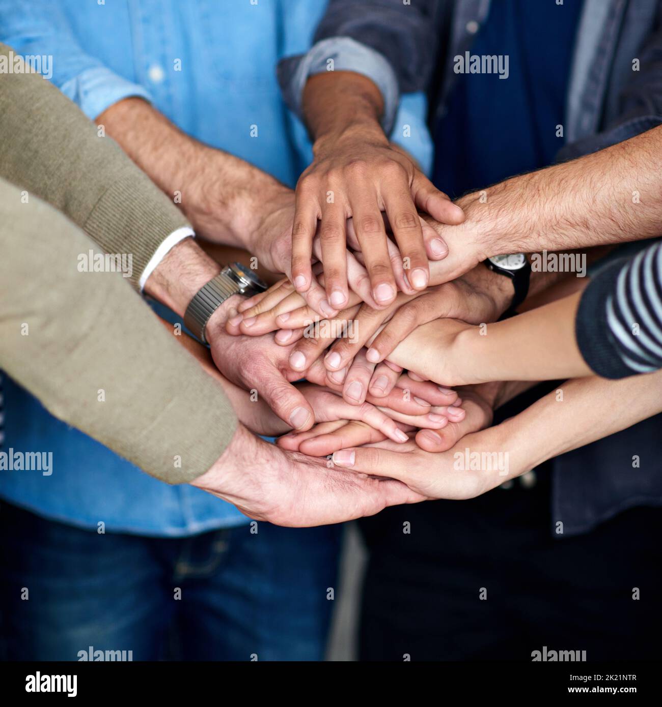 Todos juntos. Visión recortada de un grupo multiétnico que pone las manos juntas en unidad. Foto de stock