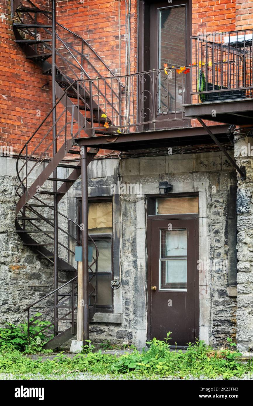Escaleras exteriores en espiral metálicas oxidadas en un edificio de ladrillo en Montreal, Canadá Foto de stock
